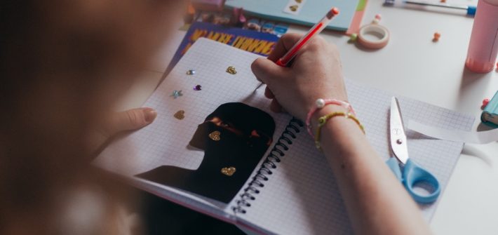 manos de una joven sobre un cuaderno donde realiza un collage