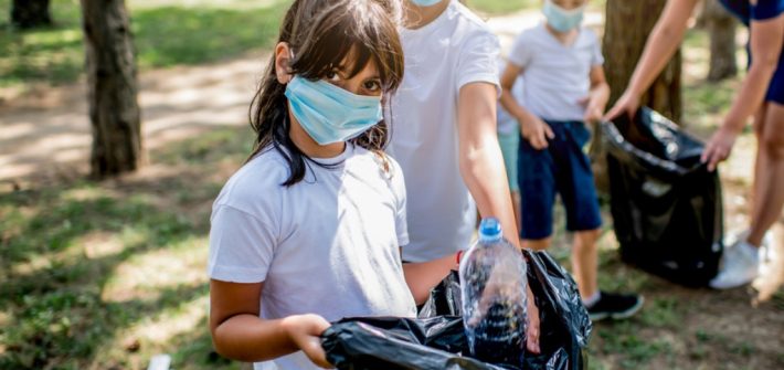 niños y niñas de la escuela recogiendo la basura juntos mientras limpian el parque público